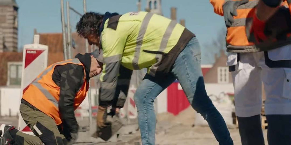 construction workers work together to pave a street